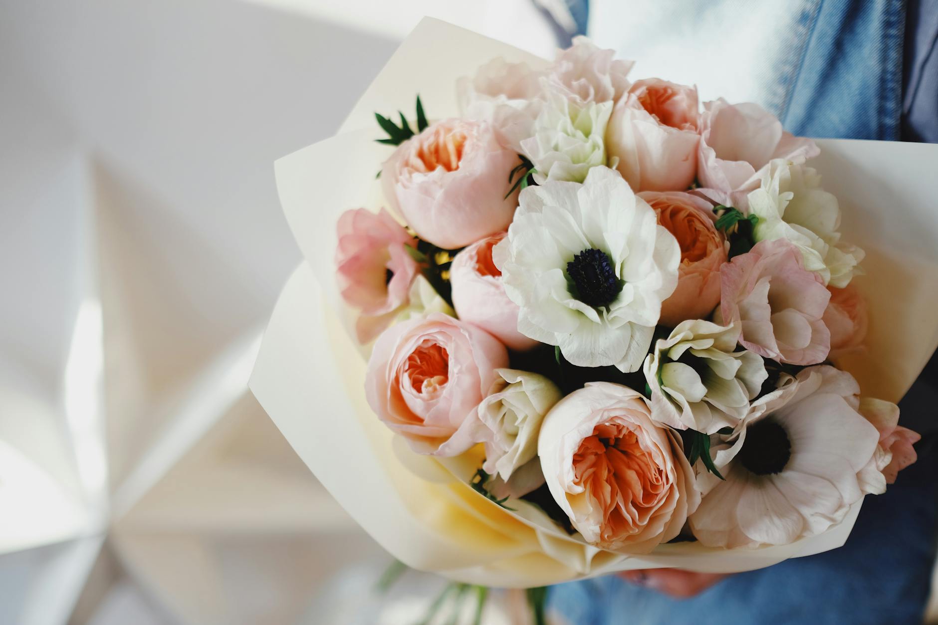 Home Charming bouquet of peach roses and white anemones perfect for romantic occasions.